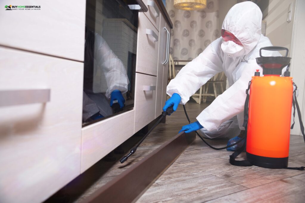 An exterminator in work clothes sprays pesticides with a spray gun against cockroaches' elimination